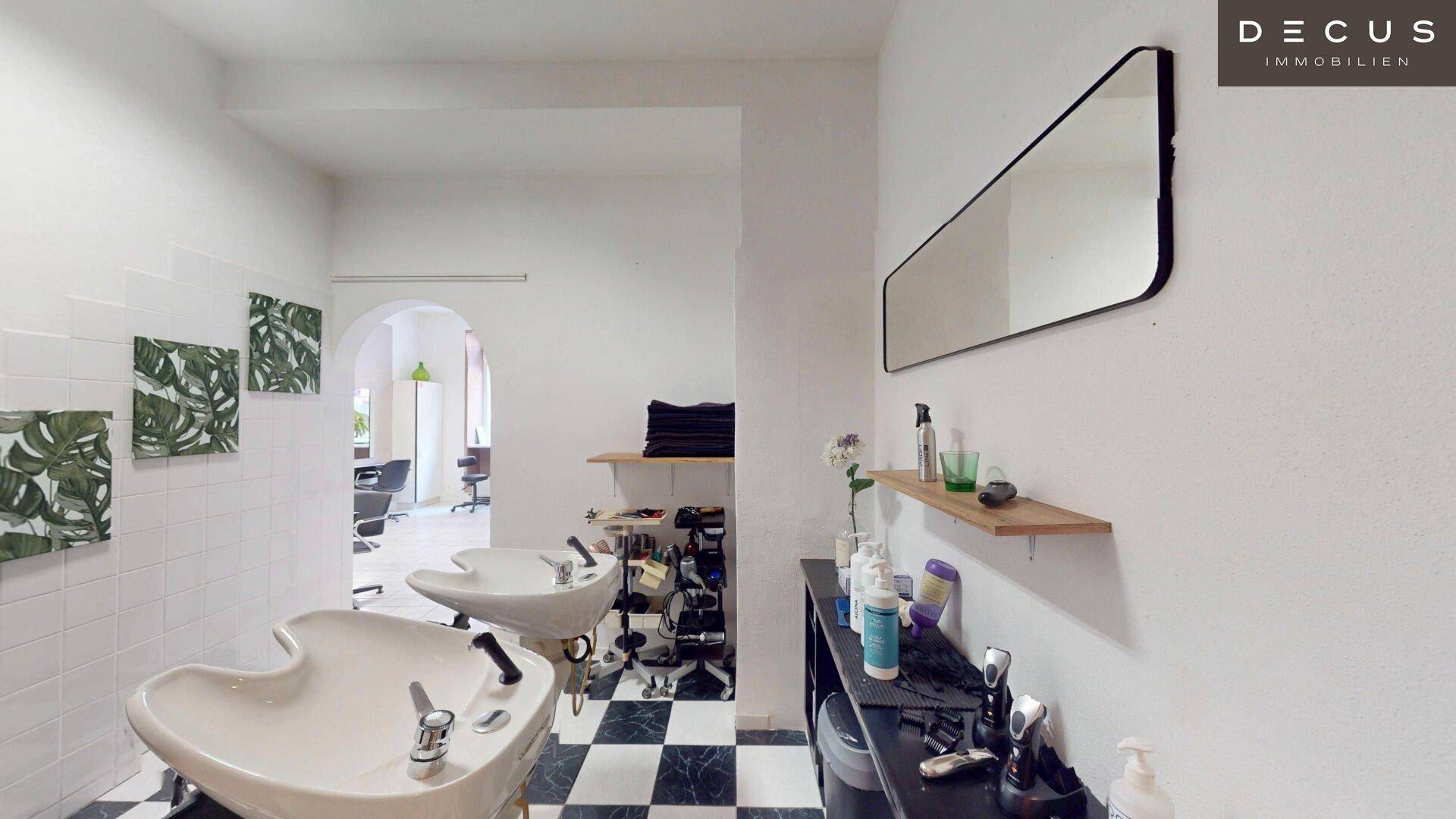 Waschbereich im Friseursalon mit zwei Haarwaschbecken und weiß gefliesten Wänden.