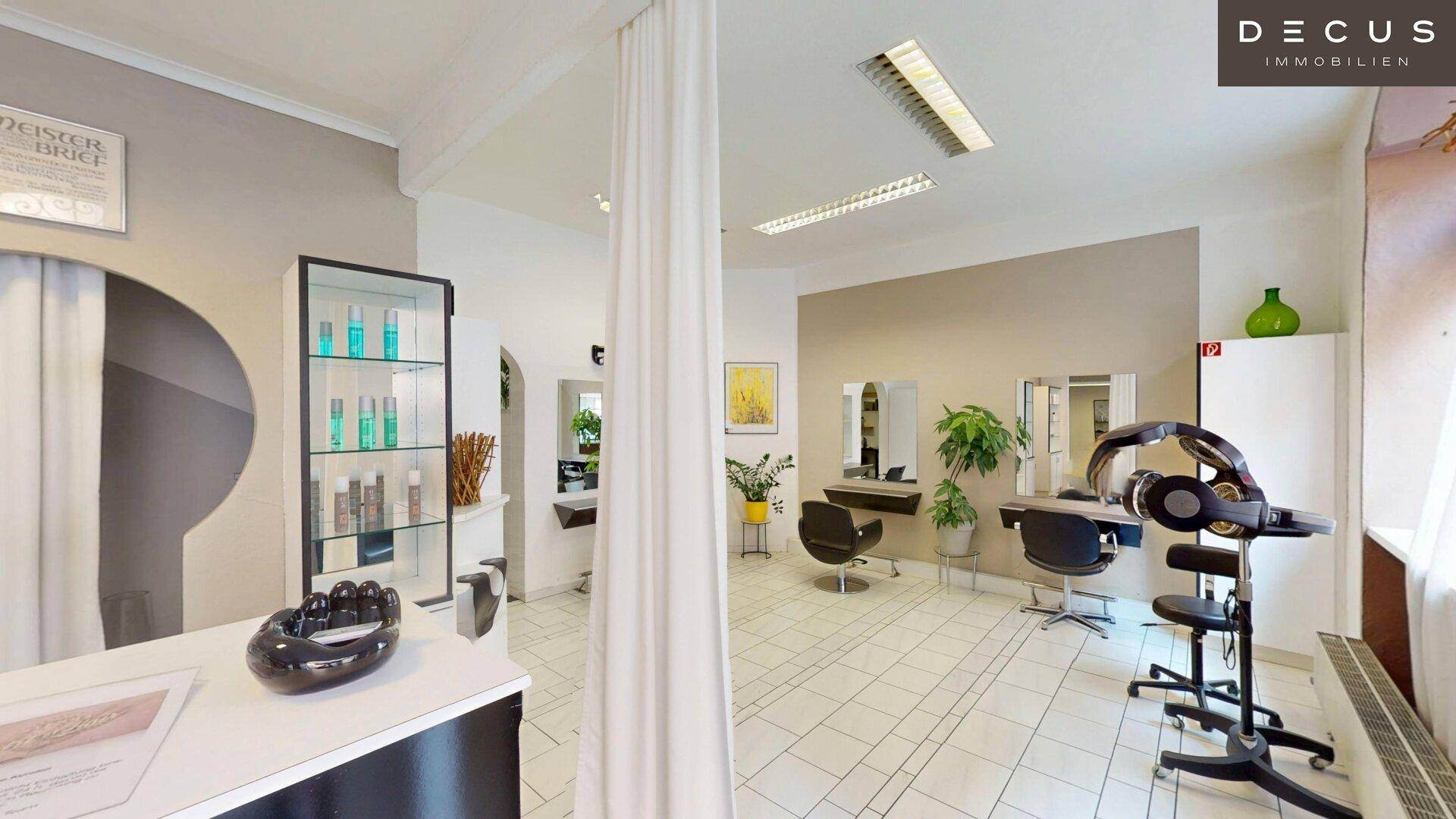 Heller Friseursalon mit mehreren Styling-Stationen, Produktregalen und weißem Fliesenboden.