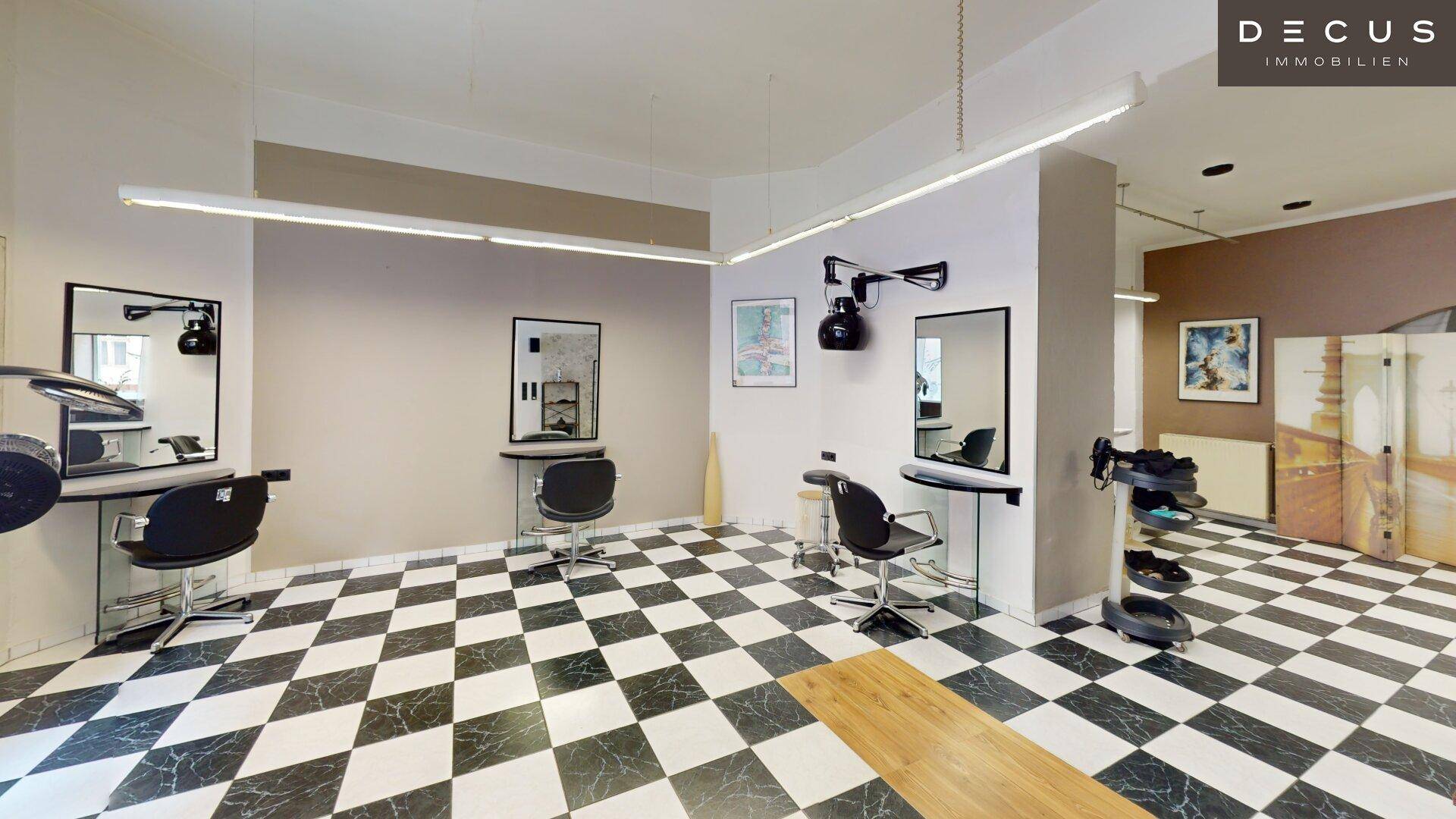 Geräumiger Friseursalon mit mehreren Styling-Stationen und auffälligem Schachbrettmuster-Fliesenboden.