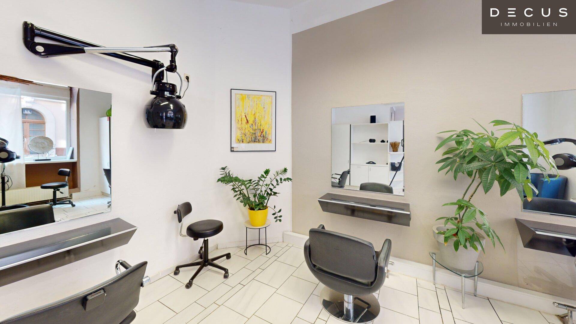 Styling-Station in einem Friseursalon mit schwenkbarem Haartrockner und Pflanzen.