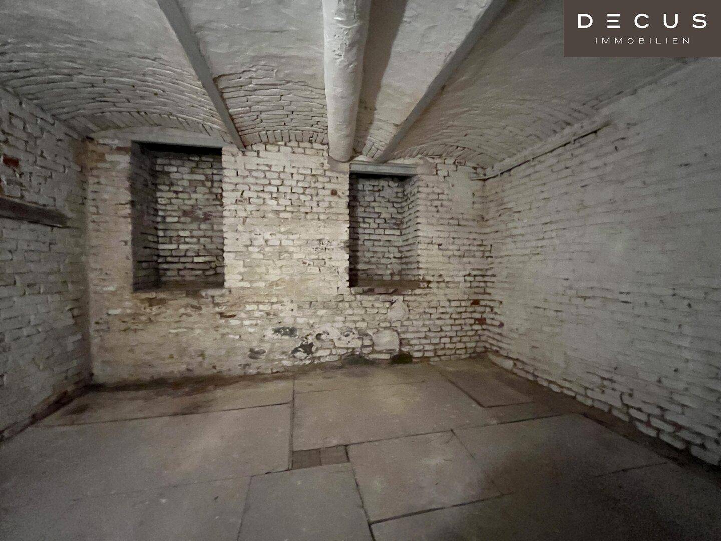 Historischer Kellerraum mit unverputzten Ziegelwänden und gewölbter Decke.