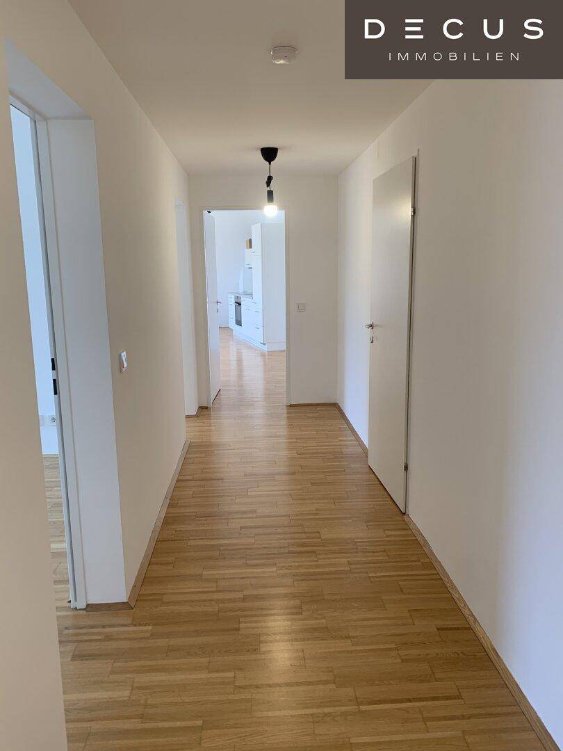 Langer, heller Flur mit Parkettboden und mehreren Türen, der zu anderen Räumen führt.