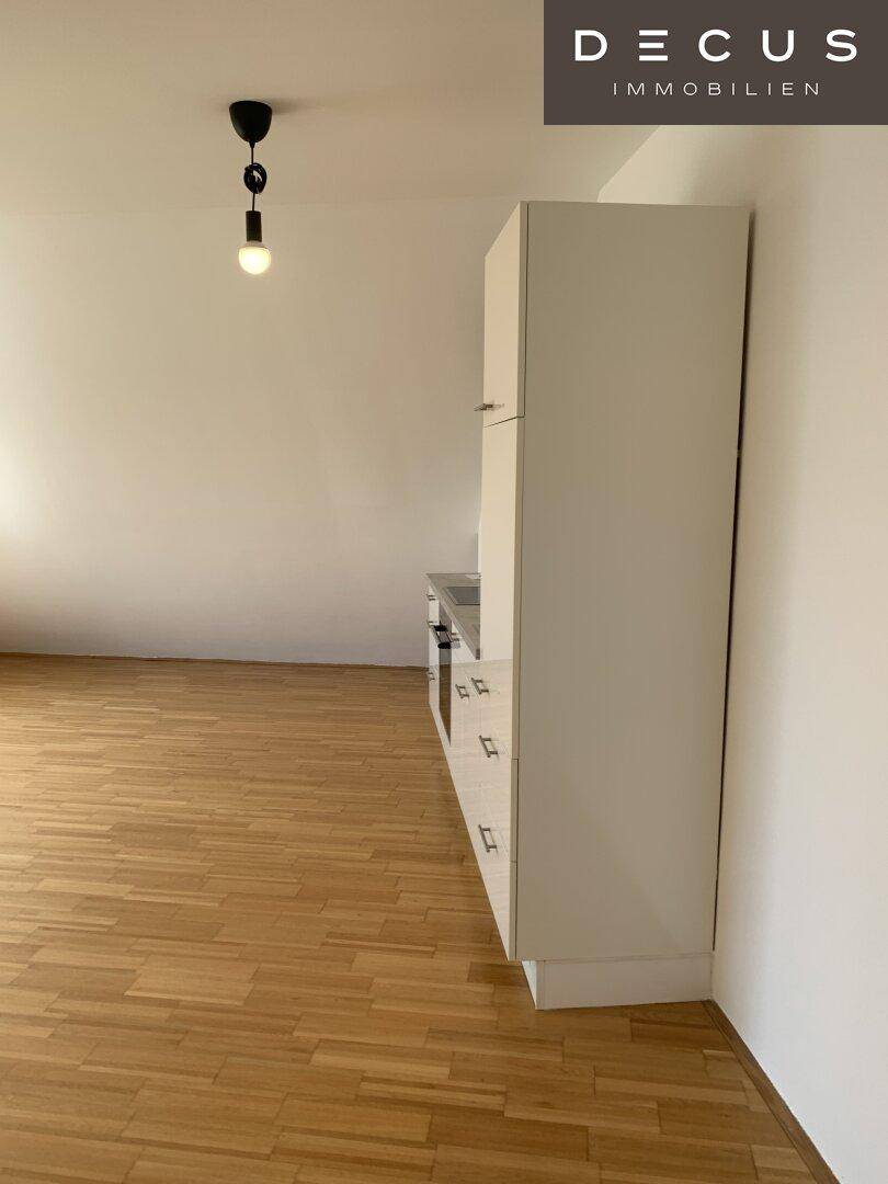 Detailansicht einer kompakten Küchenzeile mit weißen Schränken und Arbeitsplatte.