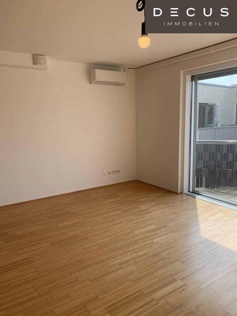 Geräumiges, leeres Wohnzimmer mit Parkettboden und großer Schiebetür zur Terrasse.