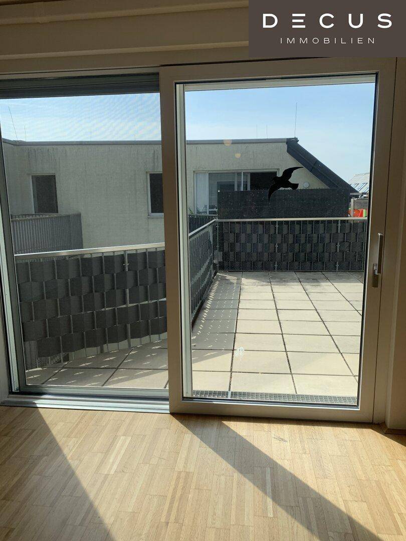 Heller Innenraum mit Blick auf eine großzügige Terrasse und die umliegende Bebauung.