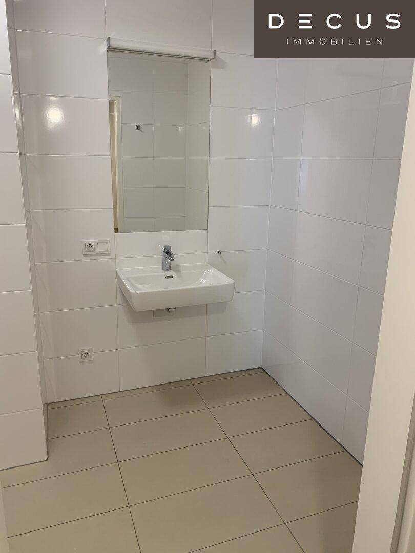 Modernes Badezimmer mit weißen Fliesen und einem eleganten Waschbecken mit Spiegel.