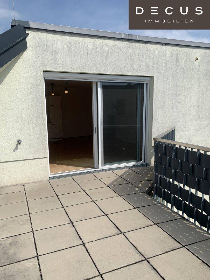 Geräumige Terrasse mit Fliesenboden und großer Schiebetür zum Innenbereich der Wohnung.