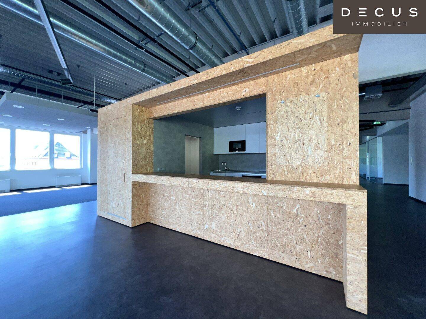 Eine moderne Küchenzeile mit Theke aus OSB-Platten, integriert in einen offenen Bürobereich.
