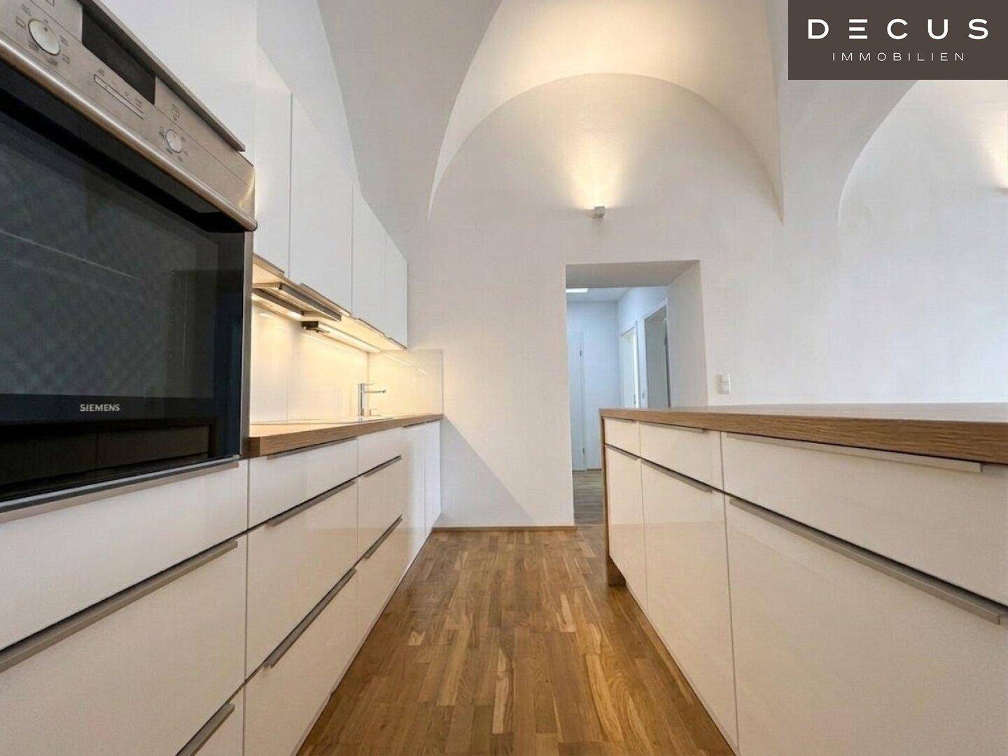 Detailansicht der modernen Küche mit weißen Schränken, Holztheke und Siemens Backofen.
