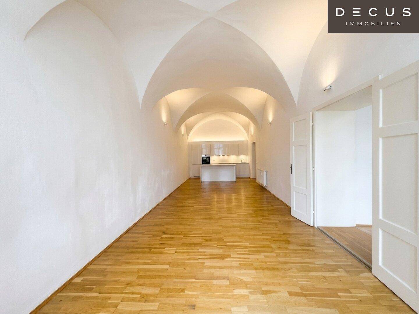 Weitläufiger Wohnbereich mit offener Küche, Gewölbedecken und elegantem Parkettboden.