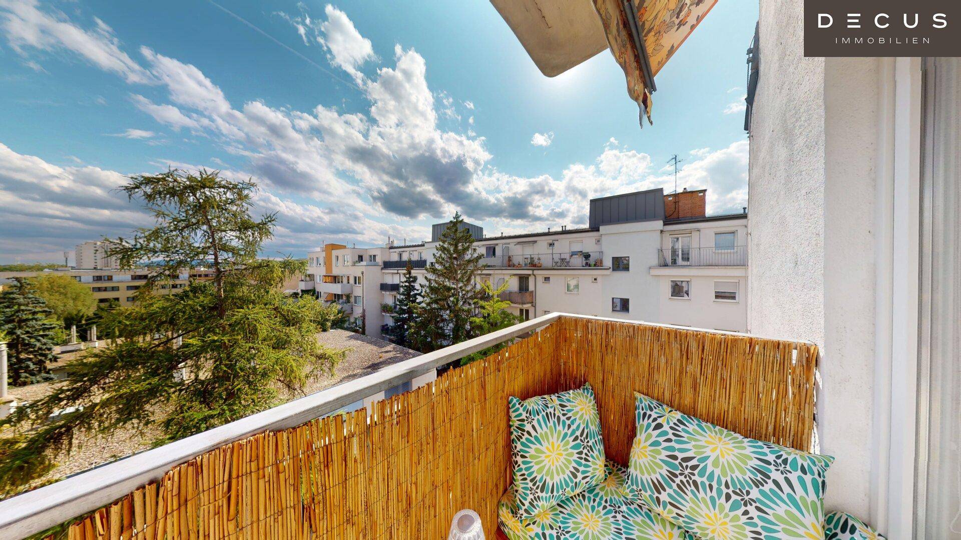 Sonniger Balkon mit Blick auf die umliegenden Gebäude und viel blauem Himmel.