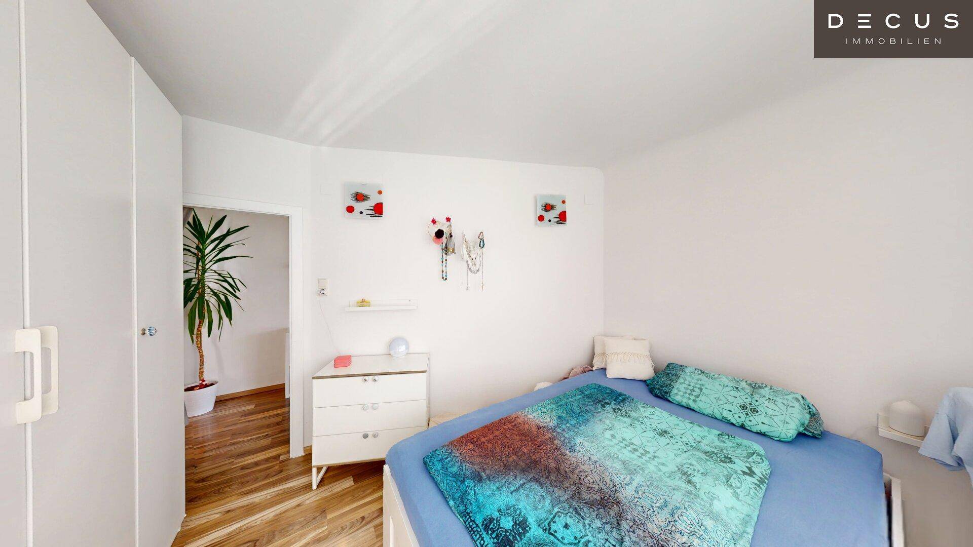 Schlafzimmer mit weißem Kleiderschrank und Zugang zu einem weiteren Raum, hell und freundlich.