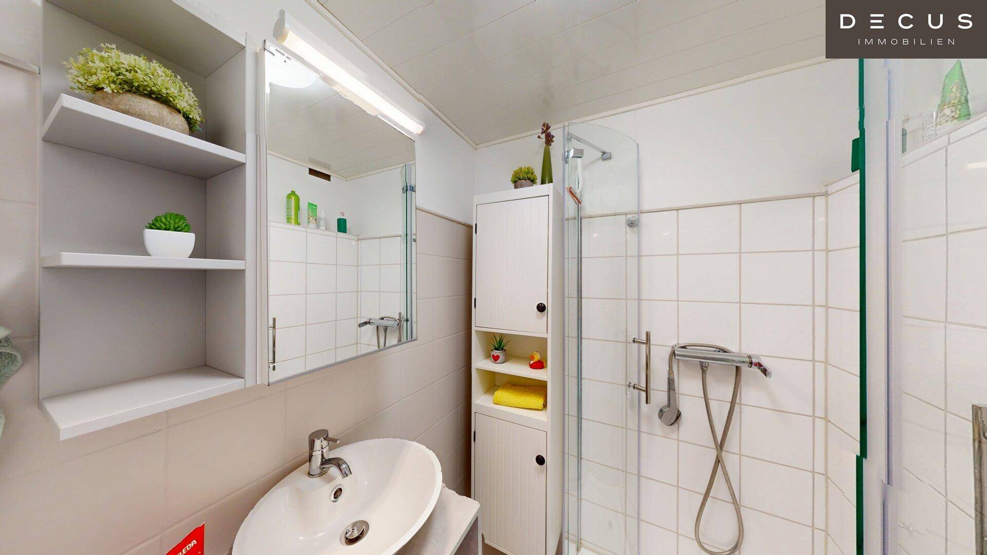 Modernes Badezimmer mit Dusche, Waschbecken, Spiegelschrank und weißen Fliesen.