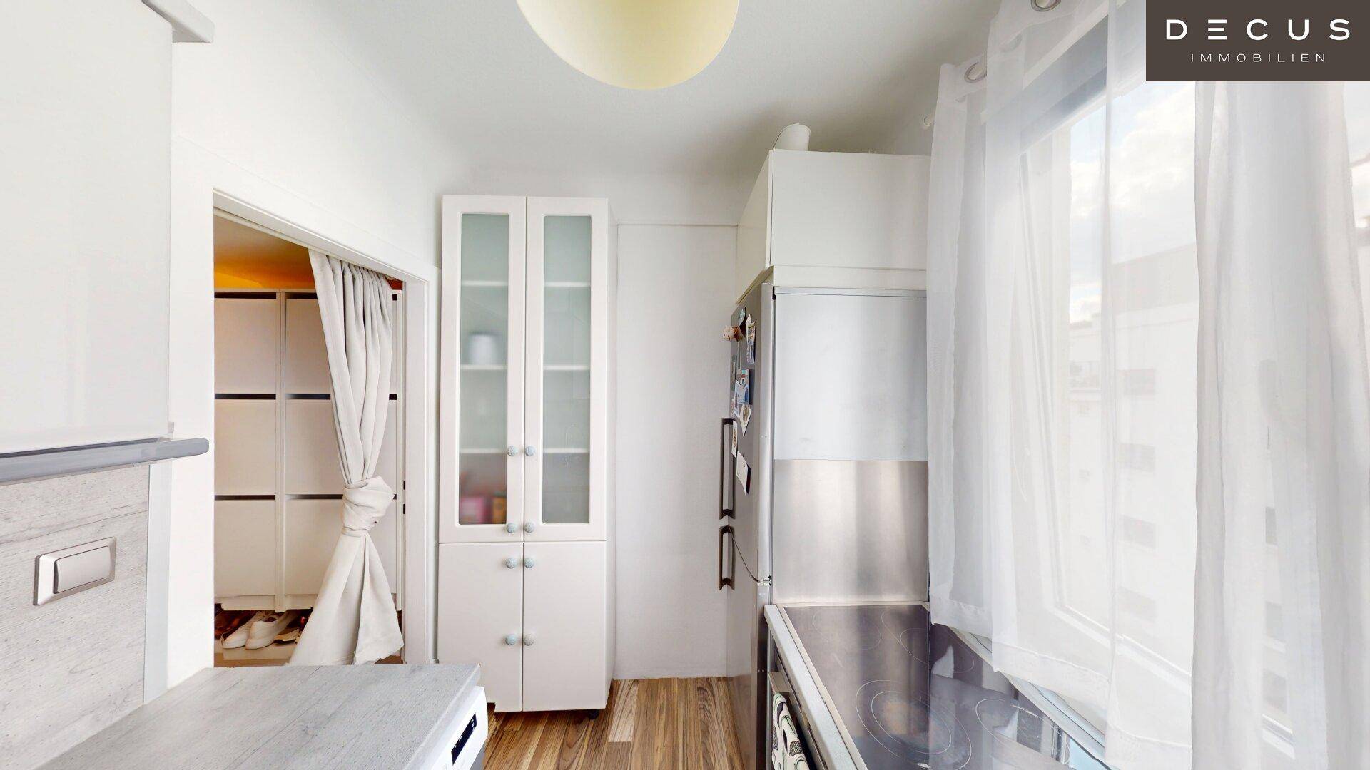 Funktionale Küche mit Kühlschrank, Kochfeld und einem praktischen Vorratsschrank.