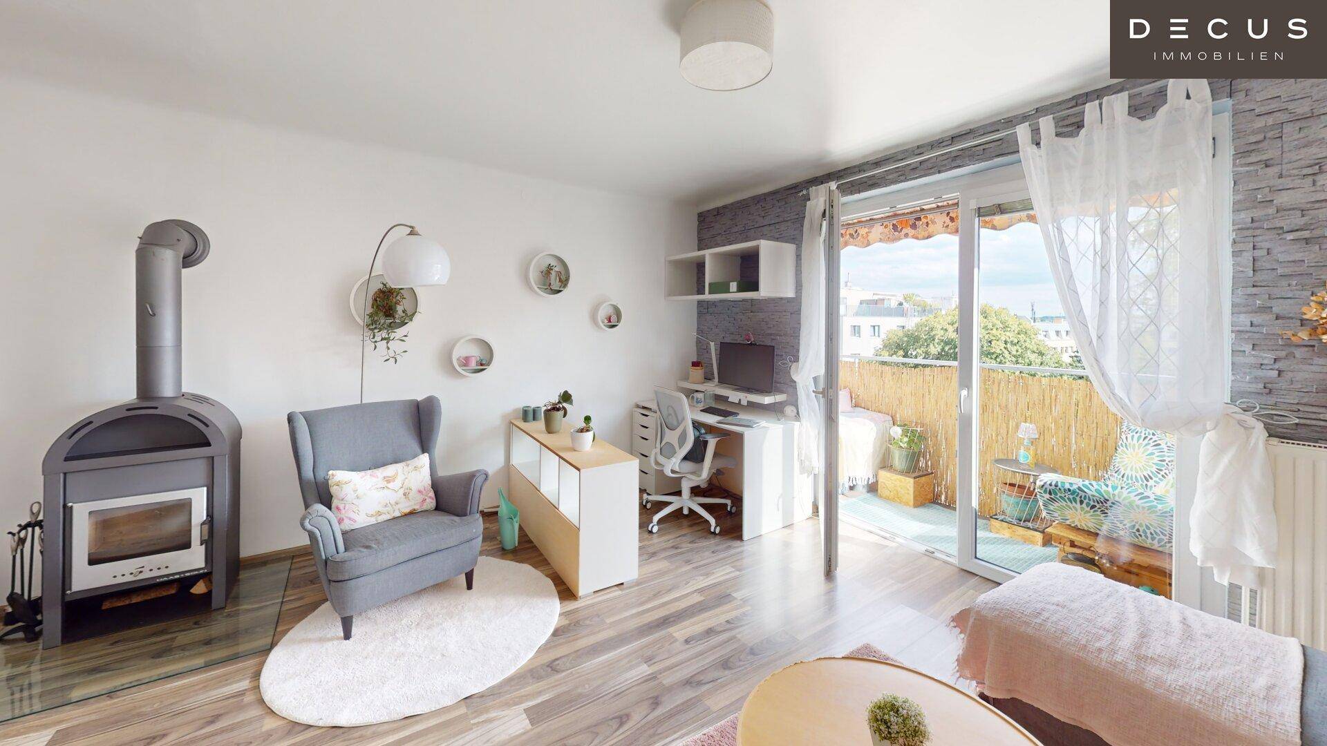 Helles Wohnzimmer mit Kaminofen, Arbeitsbereich und direktem Zugang zum Balkon.
