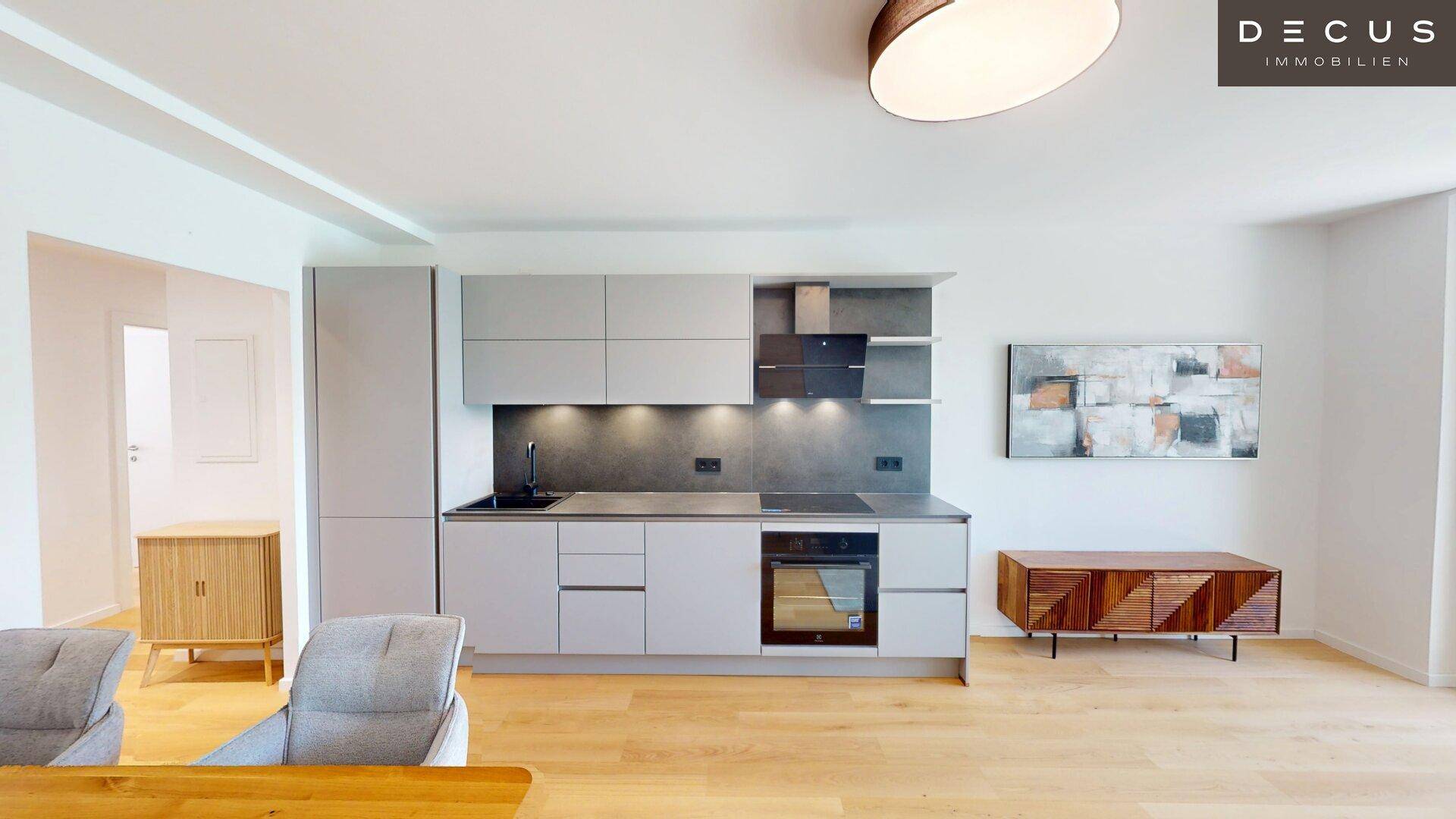 Moderne Einbauküche mit grauen Fronten, Induktionskochfeld und integriertem Backofen.