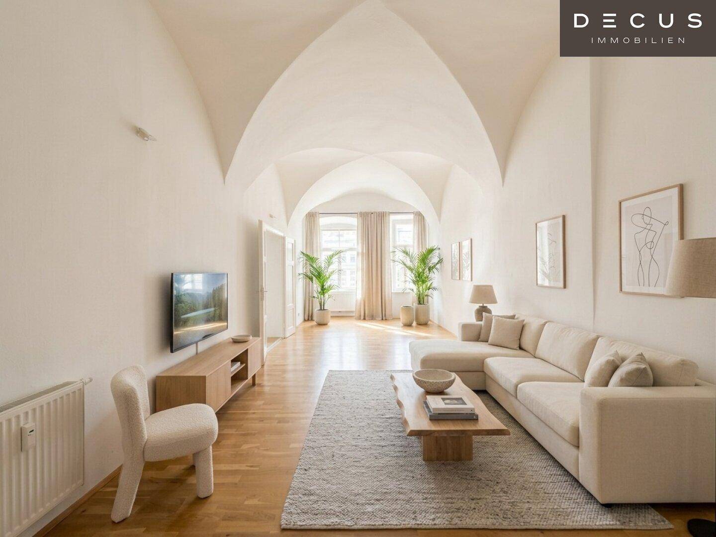 Geräumiges Wohnzimmer mit bequemer Couch, Fernseher und hohen Gewölbedecken.