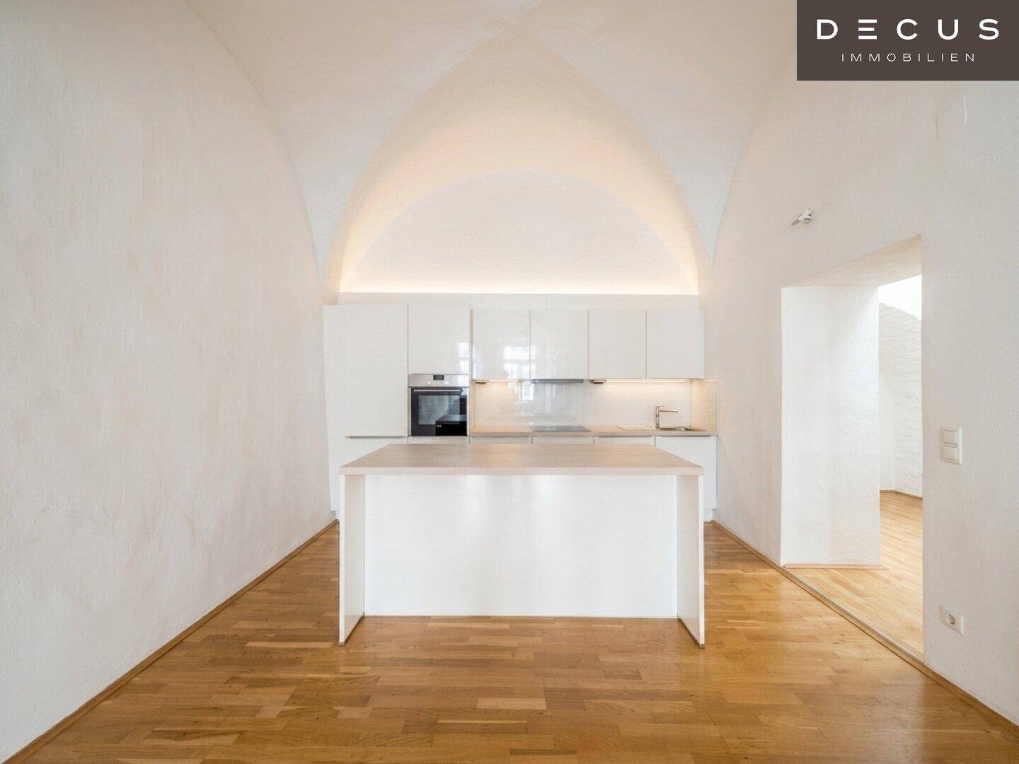 Helle, moderne Küche mit Kücheninsel, integriertem Backofen und eleganter Gewölbedecke.