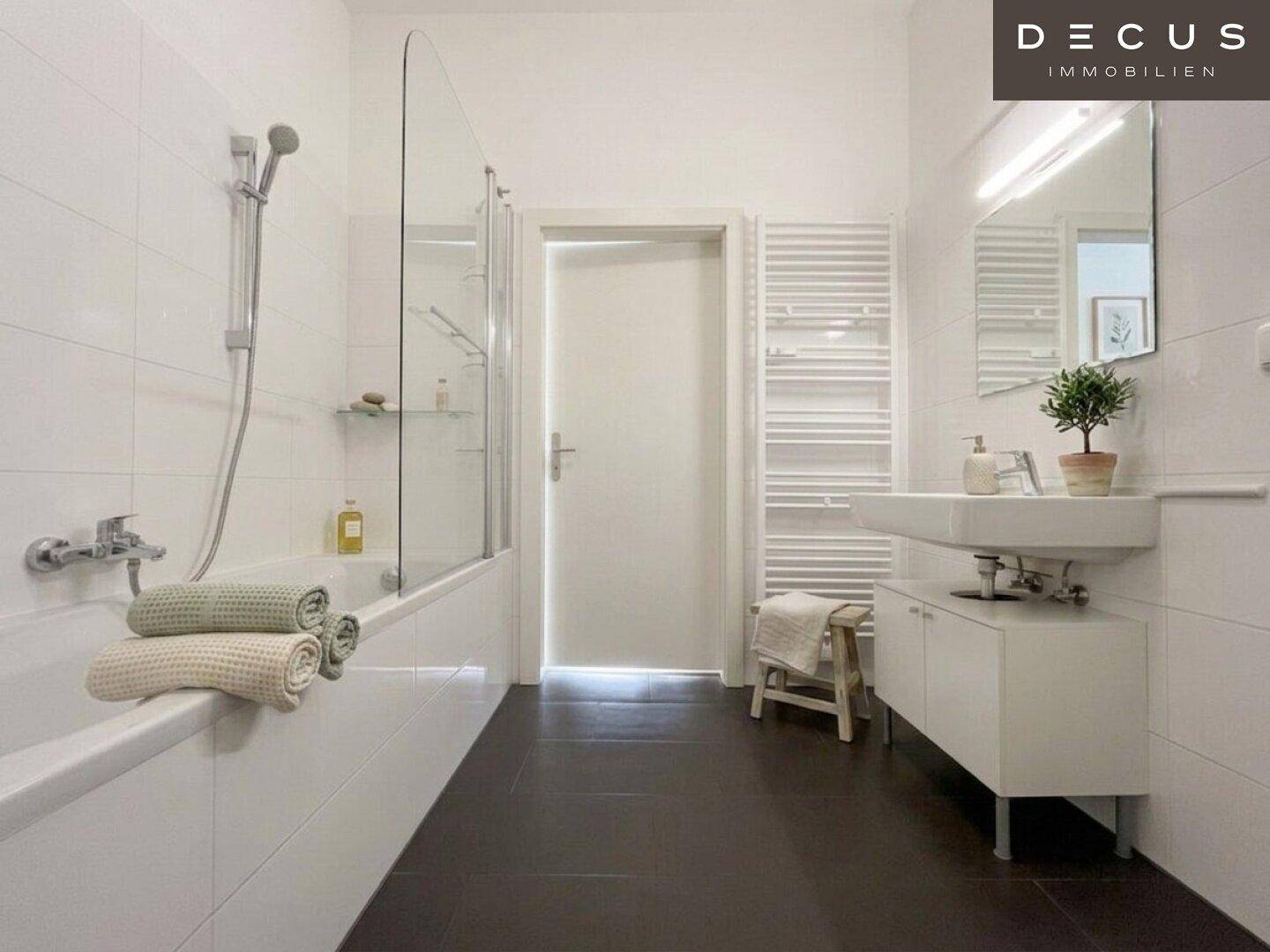 Modernes Badezimmer mit Badewanne, Duschwand, Einzelwaschbecken und beheiztem Handtuchhalter.