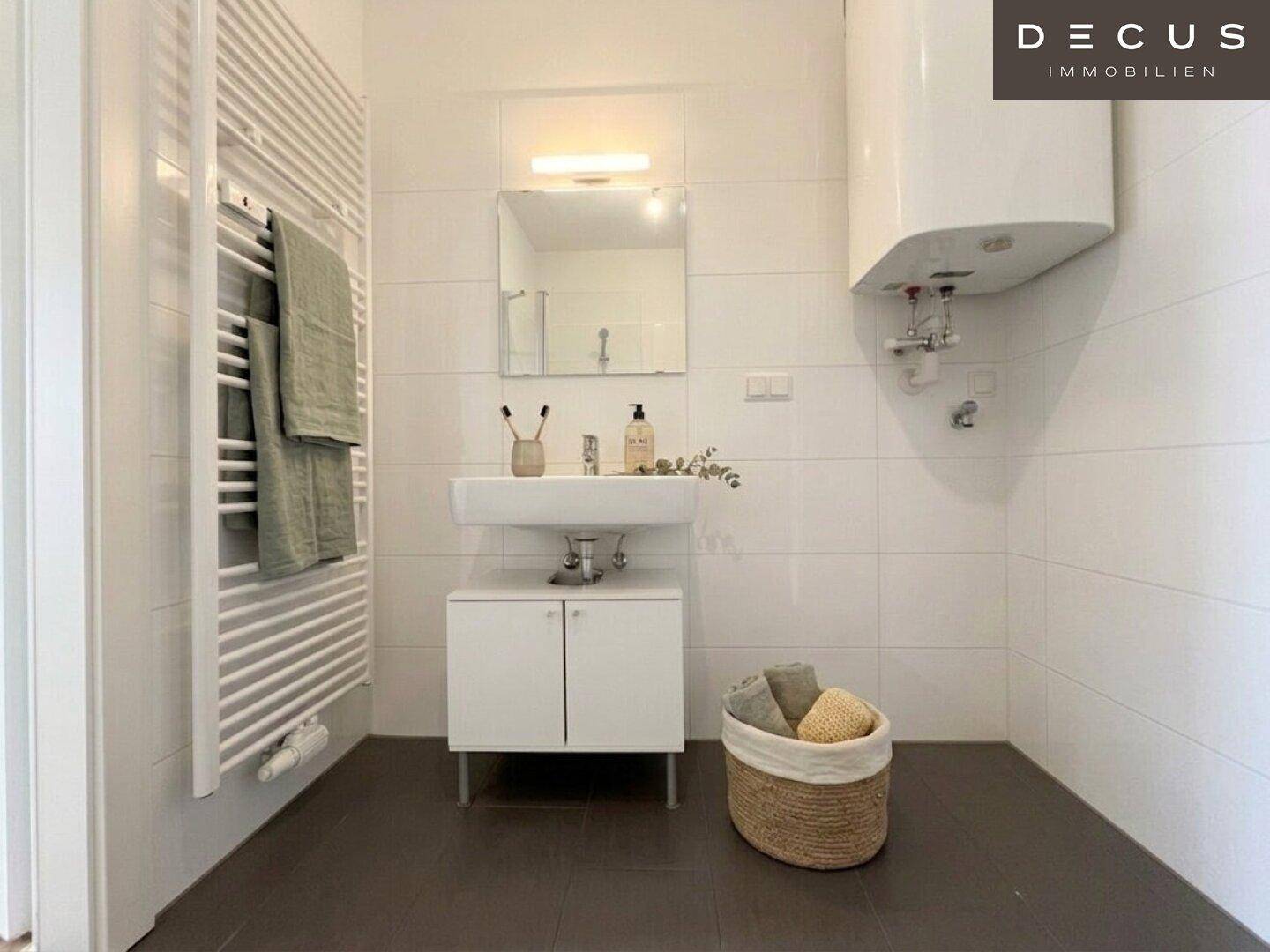 Funktionales Badezimmer mit Waschbecken, Spiegelschrank, beheiztem Handtuchhalter und Boiler.
