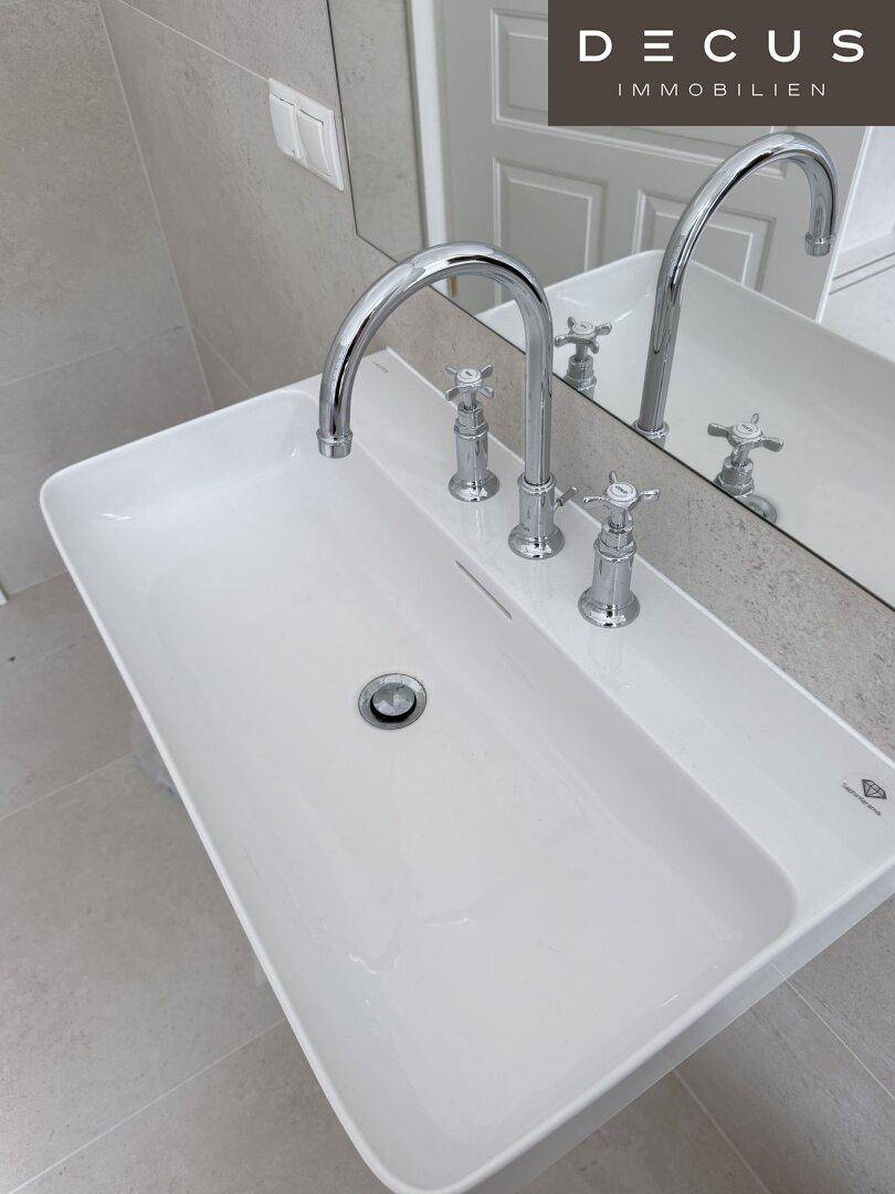 Elegantes, rechteckiges Waschbecken mit klassischen Armaturen und großem Spiegel im Badezimmer.