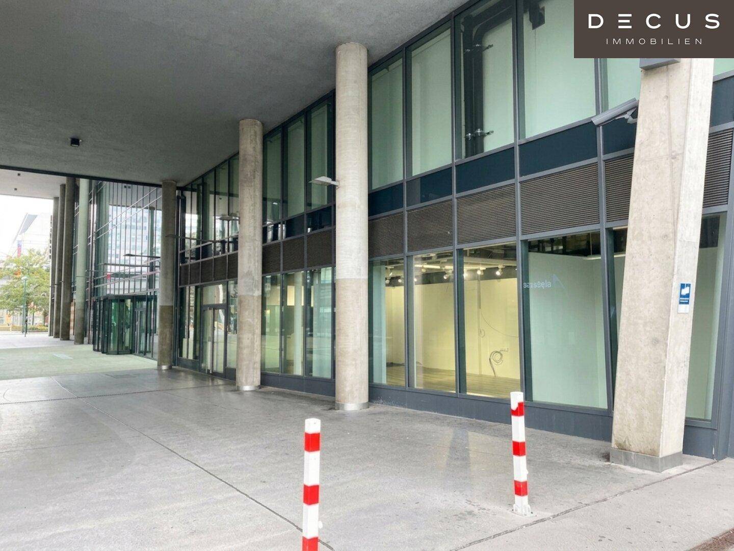 Ansicht der modernen Gebäudefassade mit großen Glasfronten und markanten Betonsäulen.