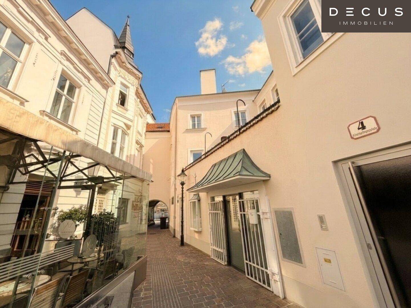 Enge Gasse mit Kopfsteinpflaster und historischen Gebäuden unter blauem Himmel.