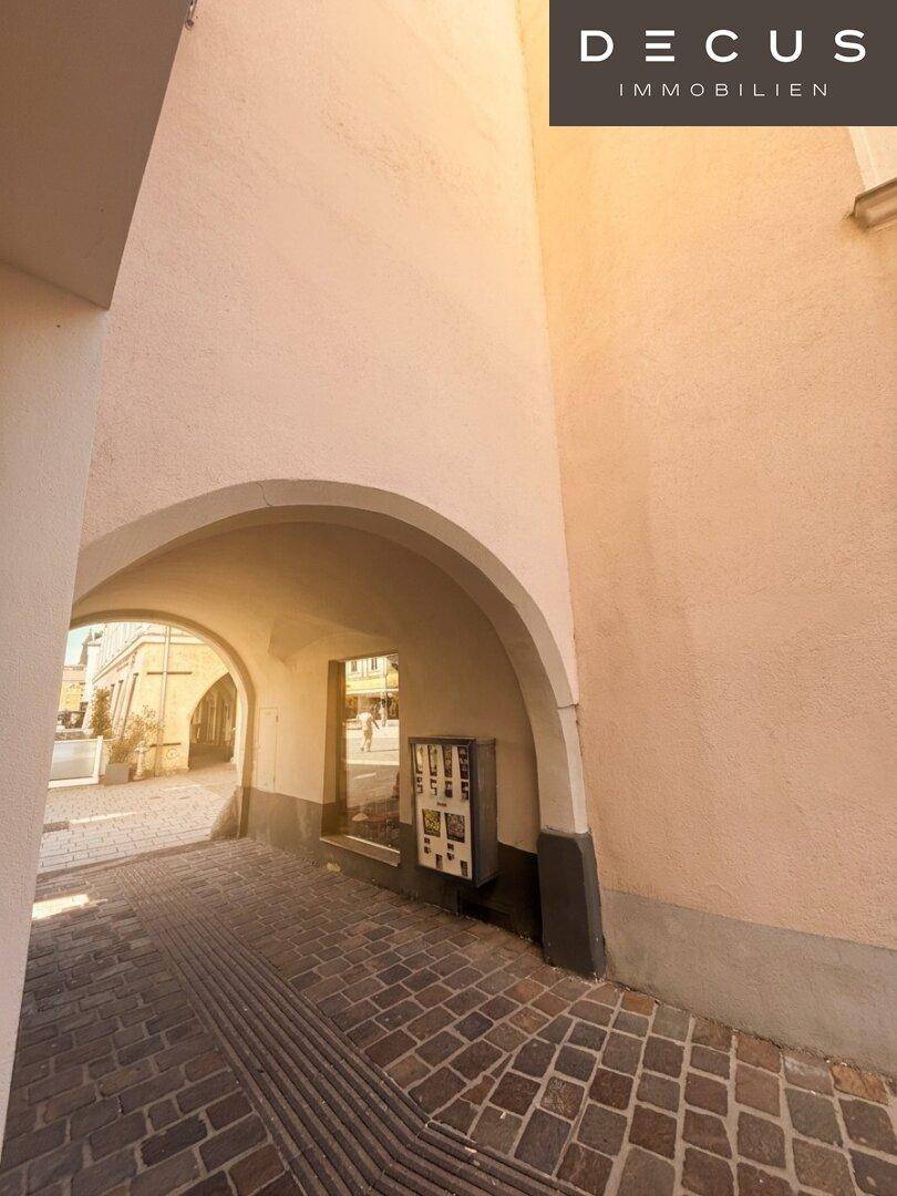 Historischer Torbogen mit gepflastertem Durchgang, der zu einer weiteren Gasse führt.