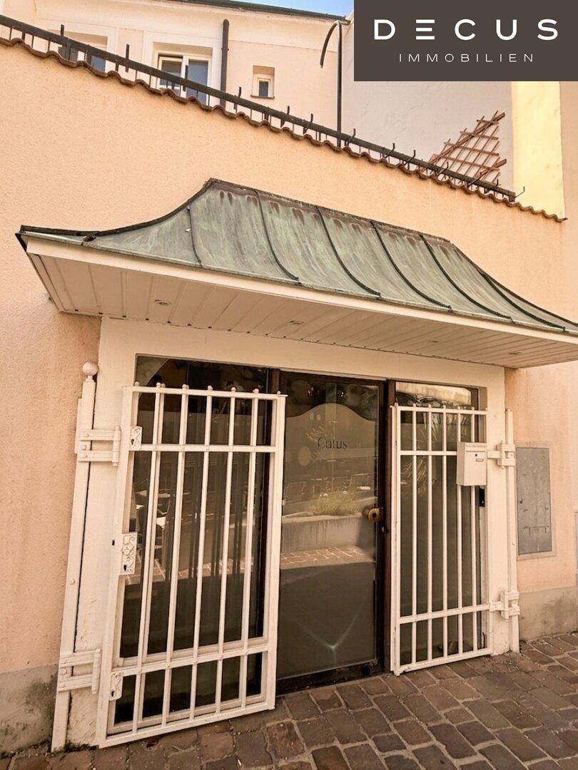 Eingangsbereich eines Geschäfts mit schmiedeeisernen Gittern und einem Vordach.