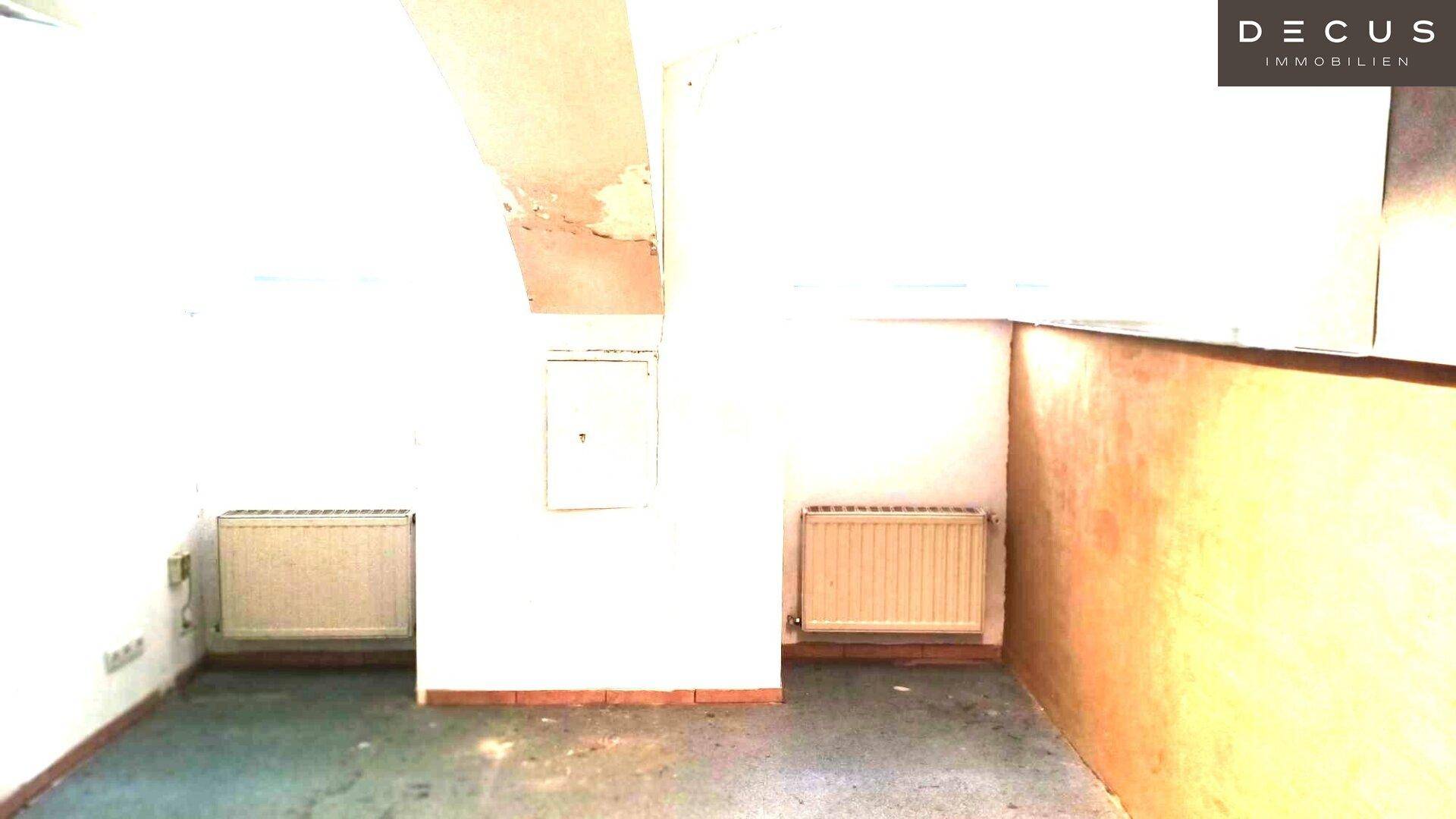 Schlichter Innenraum mit zwei Heizkörpern und Anzeichen von Abnutzung an den Wänden und der Decke.