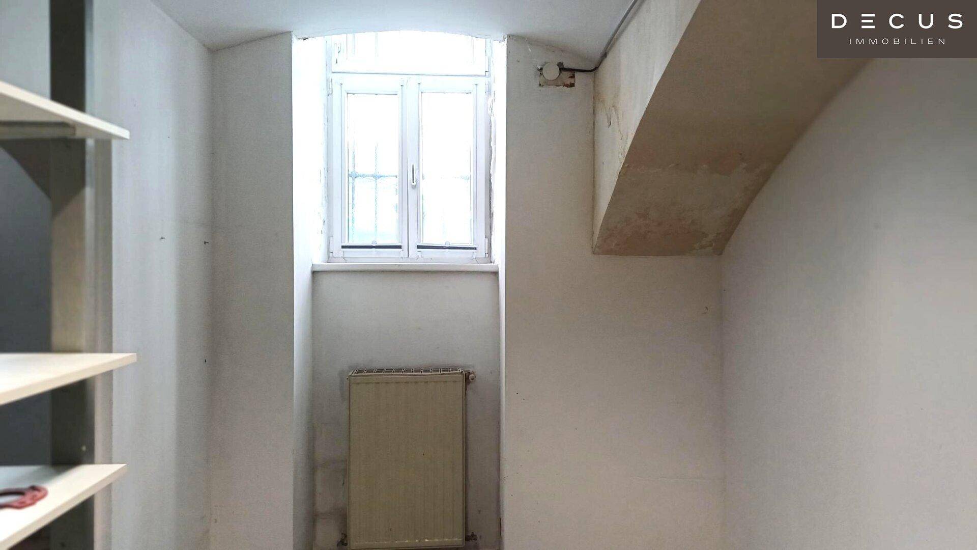 Heller Innenraum mit einem Fenster, Heizkörper darunter und Regalen an der Seite, vielseitig nutzbar.