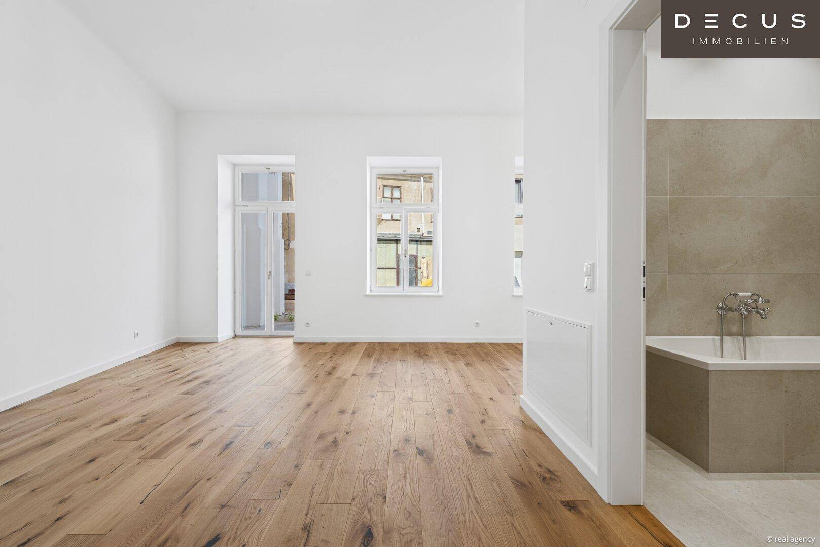 Heller Raum mit neu verlegtem Holzboden und Zugang zu einem möglichen Balkon.