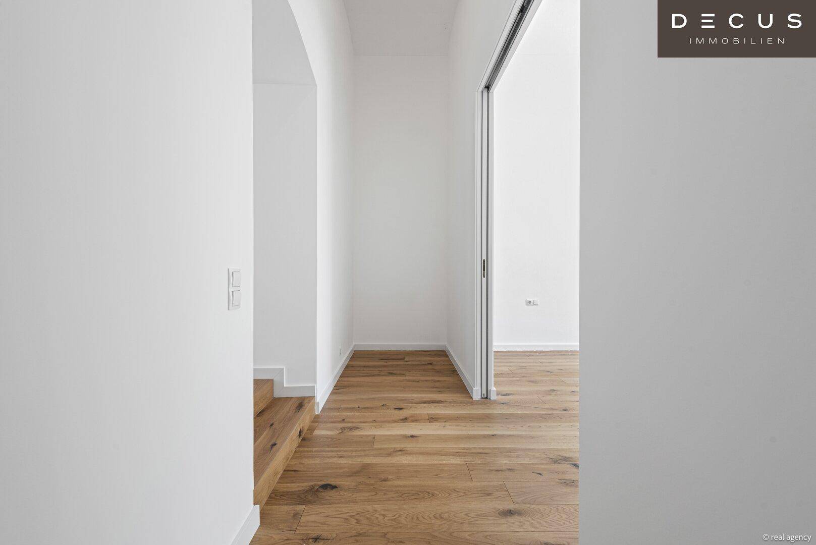 Heller Flur mit Holzboden und Schiebetür zu einem angrenzenden Zimmer.