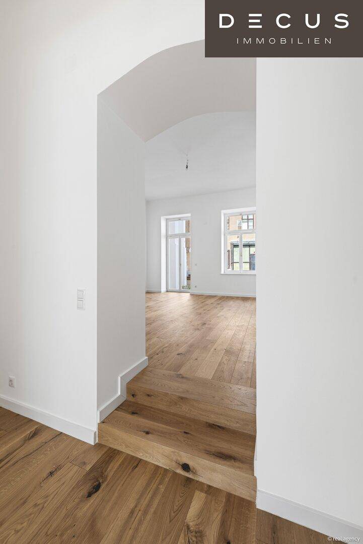 Heller Flur mit Holzboden und einem eleganten Rundbogen als Durchgang.