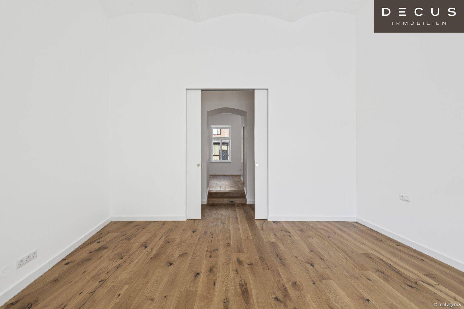Heller Raum mit Holzboden und Schiebetür, ideal als Schlaf- oder Arbeitszimmer.