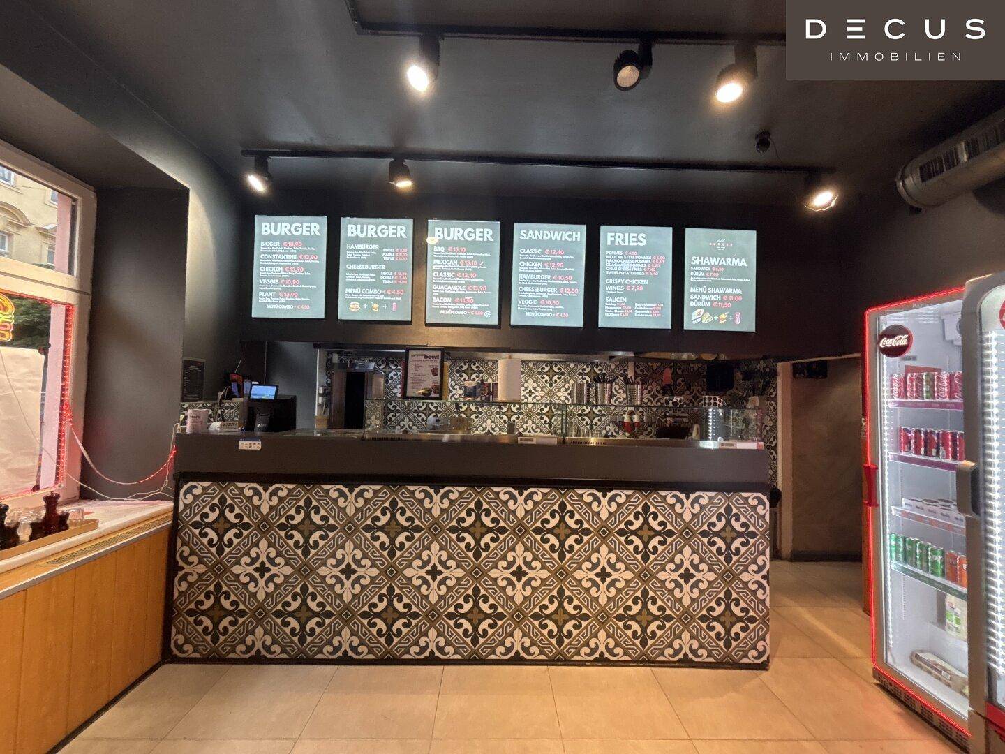 Thekenbereich eines Schnellrestaurants mit Speisekarten und dekorativen Fliesen an der Front.