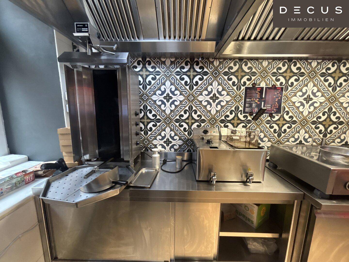 Bereich der Restaurantküche mit Dönergrill, Fritteuse und Edelstahlarbeitsflächen.