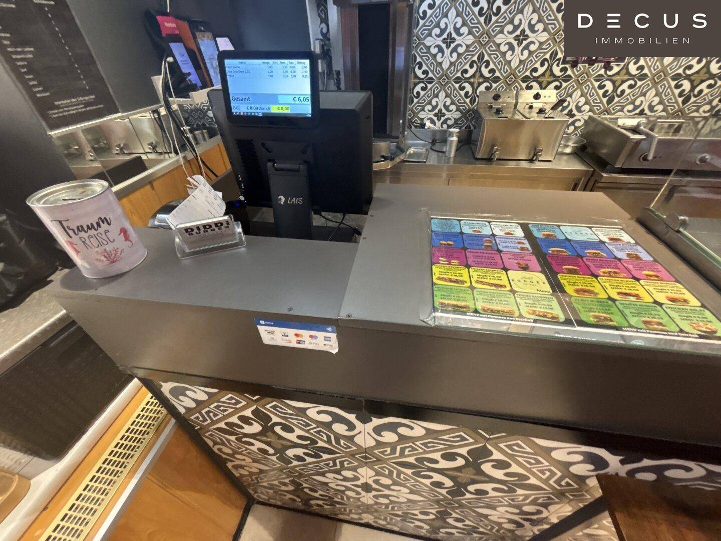 Kassenbereich eines Imbisses mit Bestellterminal und Fliesenmuster an der Theke, bereit für den Betrieb.