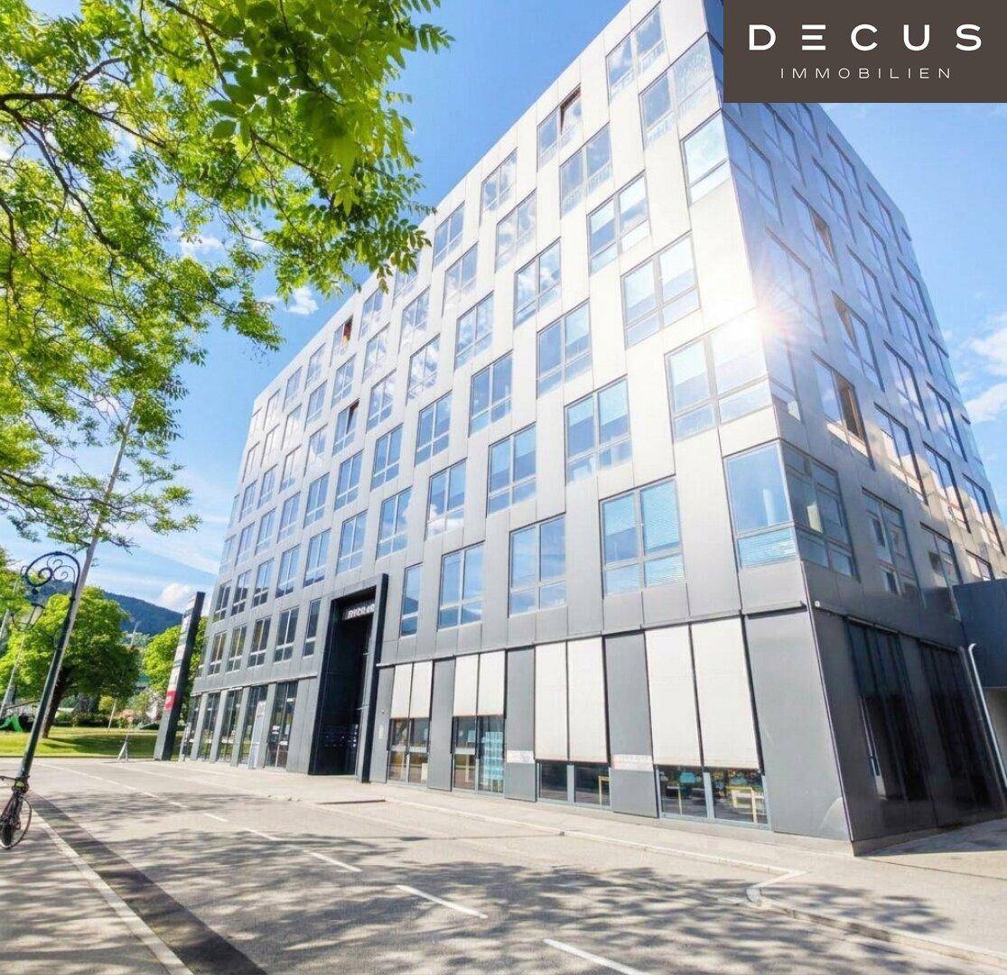 Modernes Bürogebäude mit vielen Glasfenstern und einer markanten Fassade an einem sonnigen Tag.