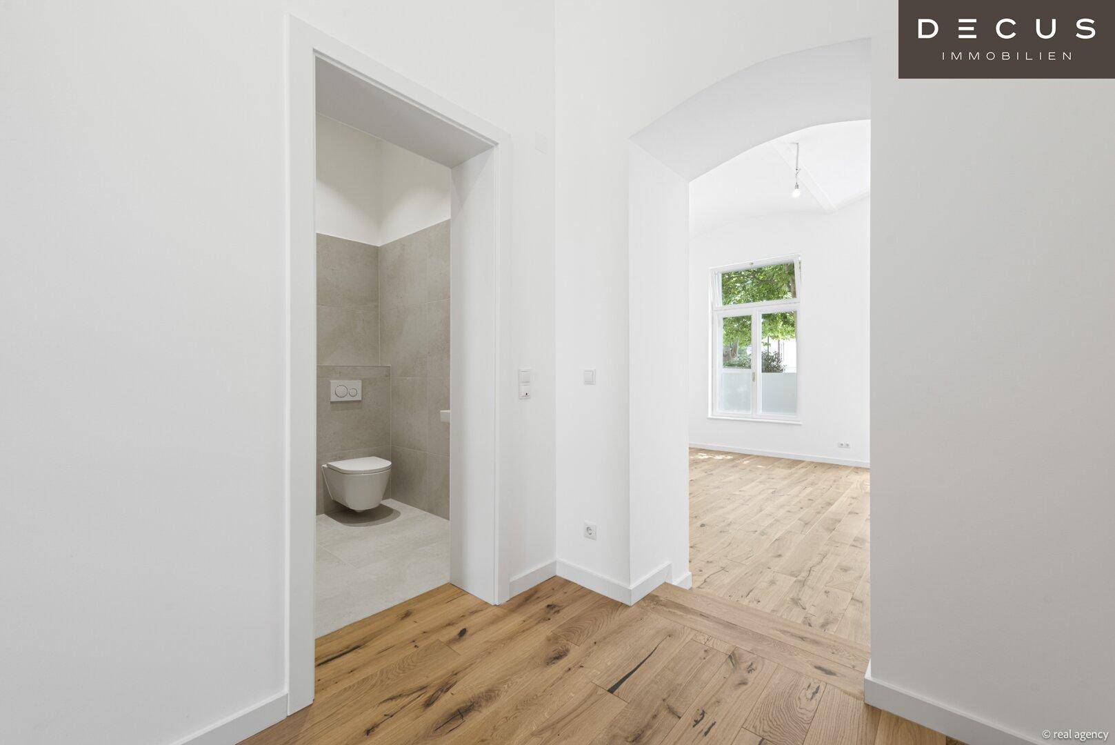 Modernes Gäste-WC mit wandhängender Toilette und hellen Fliesen an Wänden und Boden.