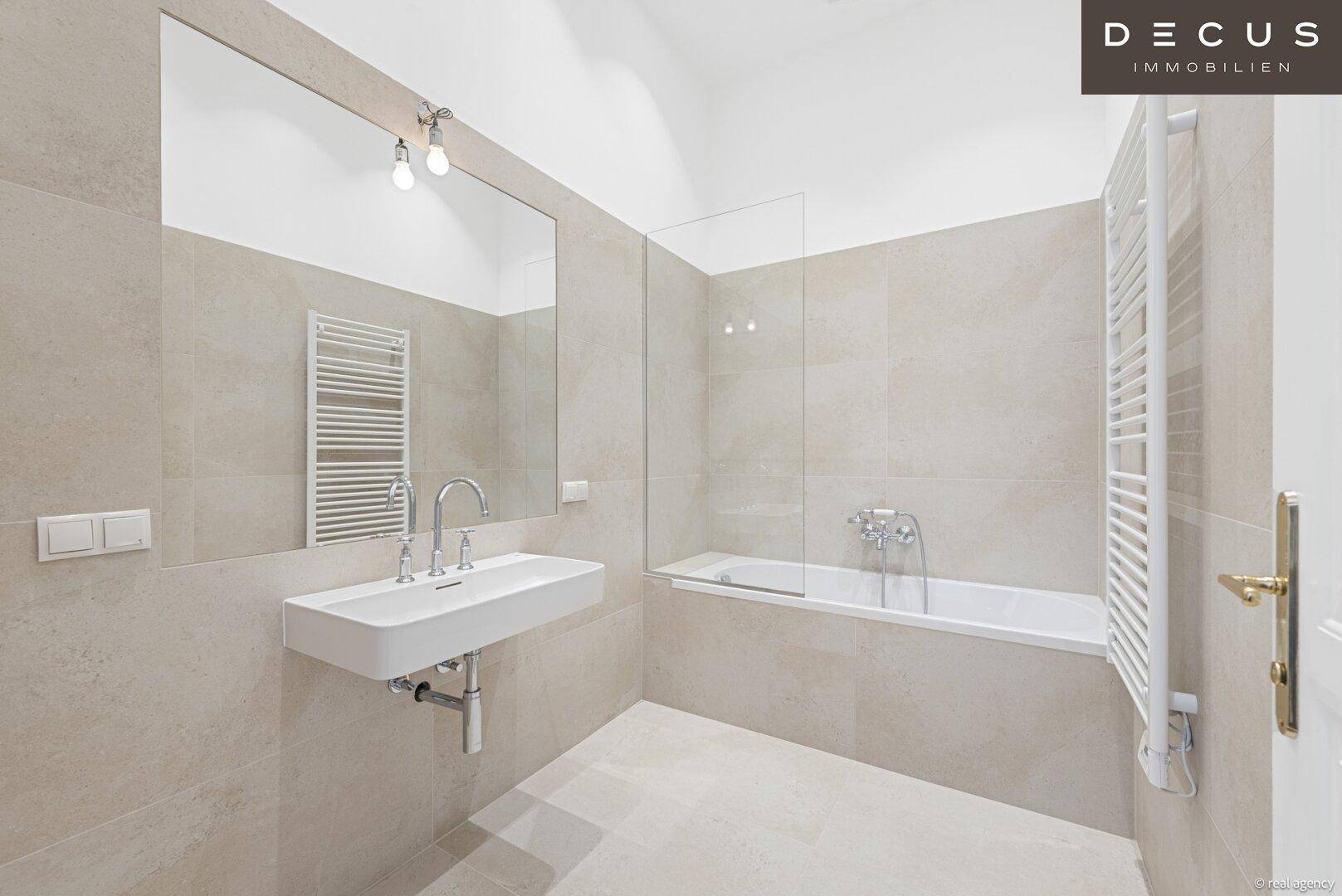 Modernes Badezimmer mit Badewanne, Waschtisch und beheiztem Handtuchhalter.
