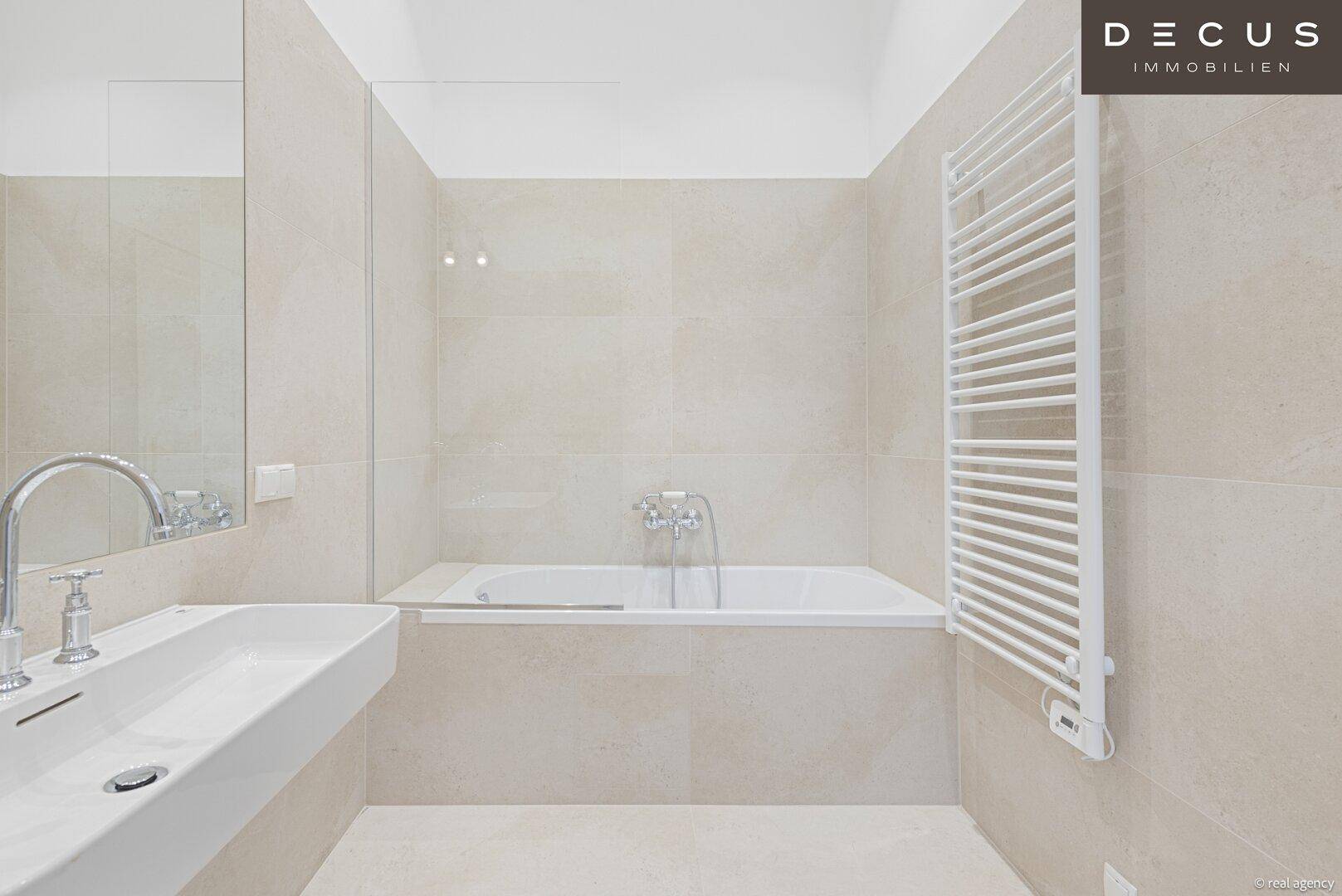 Helles Badezimmer mit Badewanne, modernem Waschtisch und großem Spiegel.
