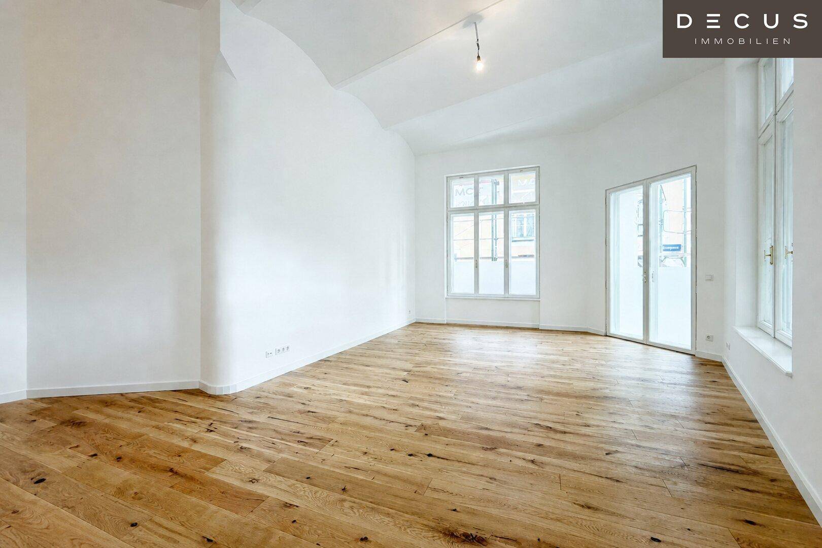 Heller, leerer Raum mit neuem Holzplankenboden und großen Fenstern, bereit zur individuellen Gestaltung.