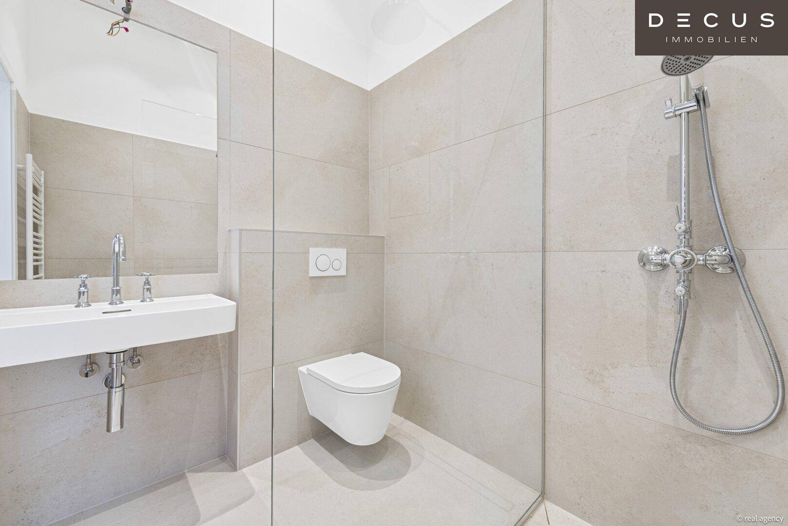 Modernes Badezimmer mit ebenerdiger Dusche, wandhängendem WC und elegantem Einzelwaschbecken.
