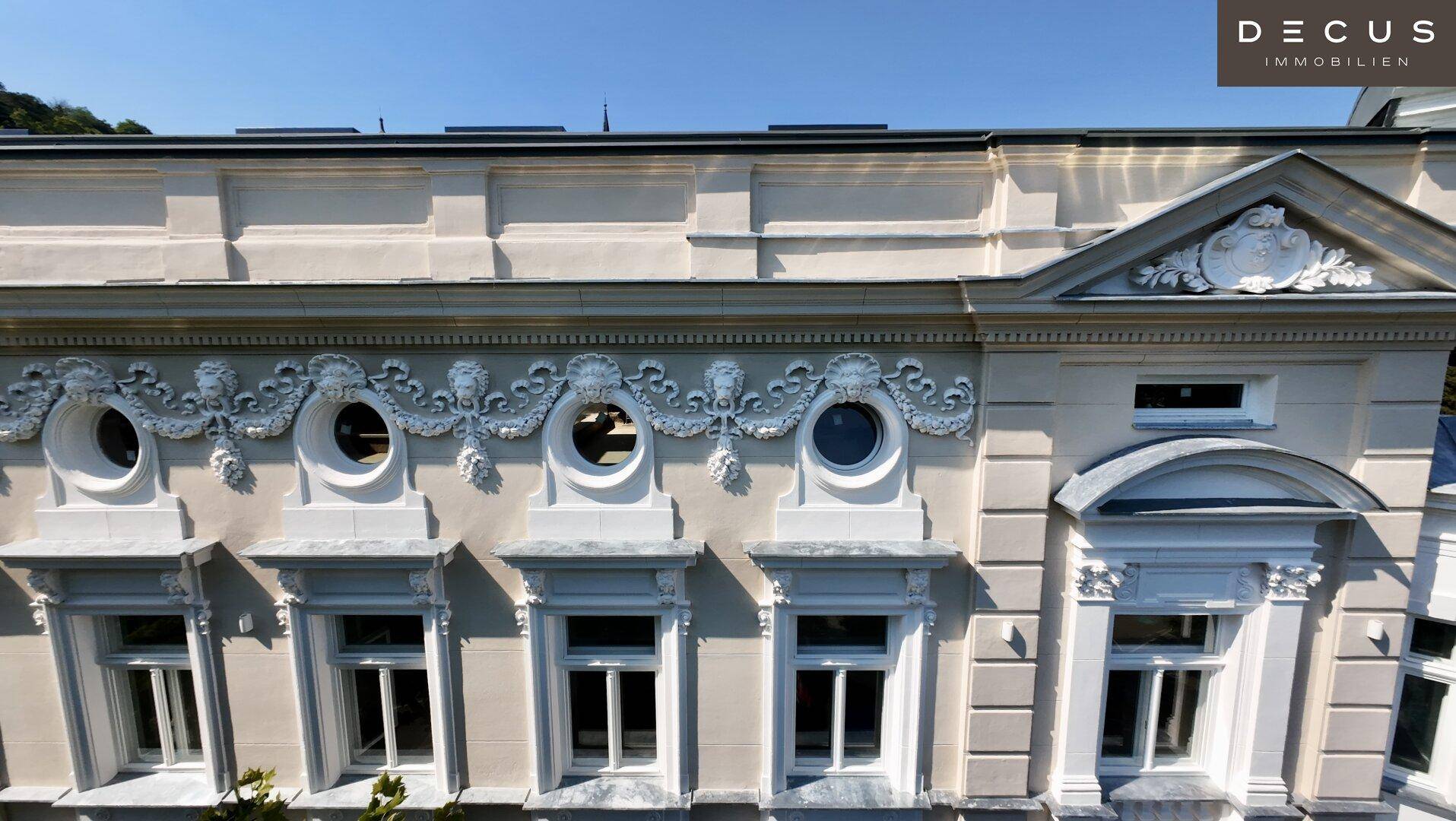 Fassadendetail mit reich verzierten Fenstern und Stuckelementen, die den historischen Charakter betonen.