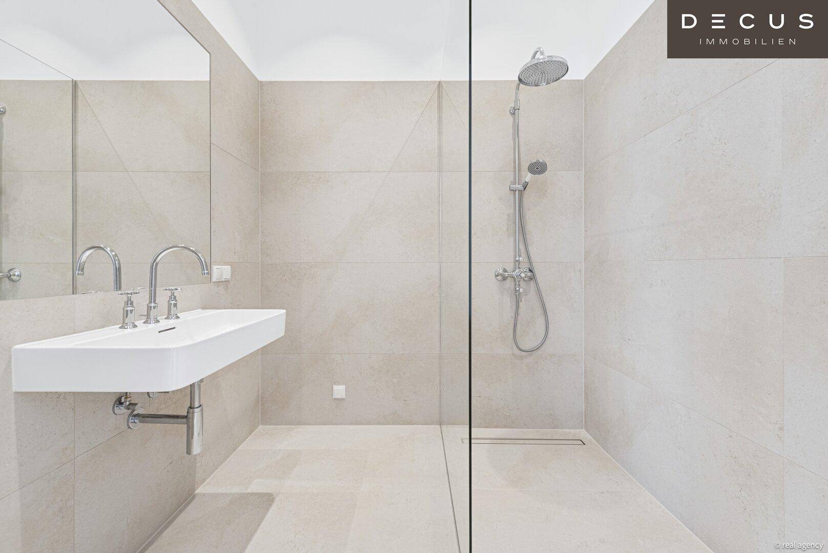 Elegantes Badezimmer mit begehbarer Dusche, modernem Waschbecken und großem Spiegel.