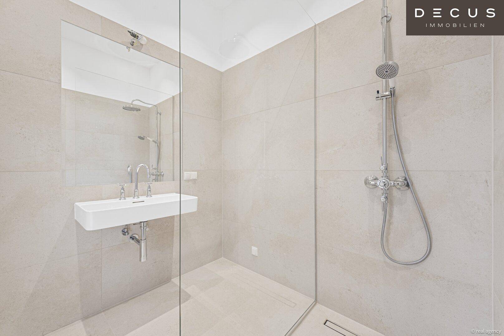 Modernes Badezimmer mit begehbarer Dusche, Wandwaschbecken und großformatigen Fliesen.