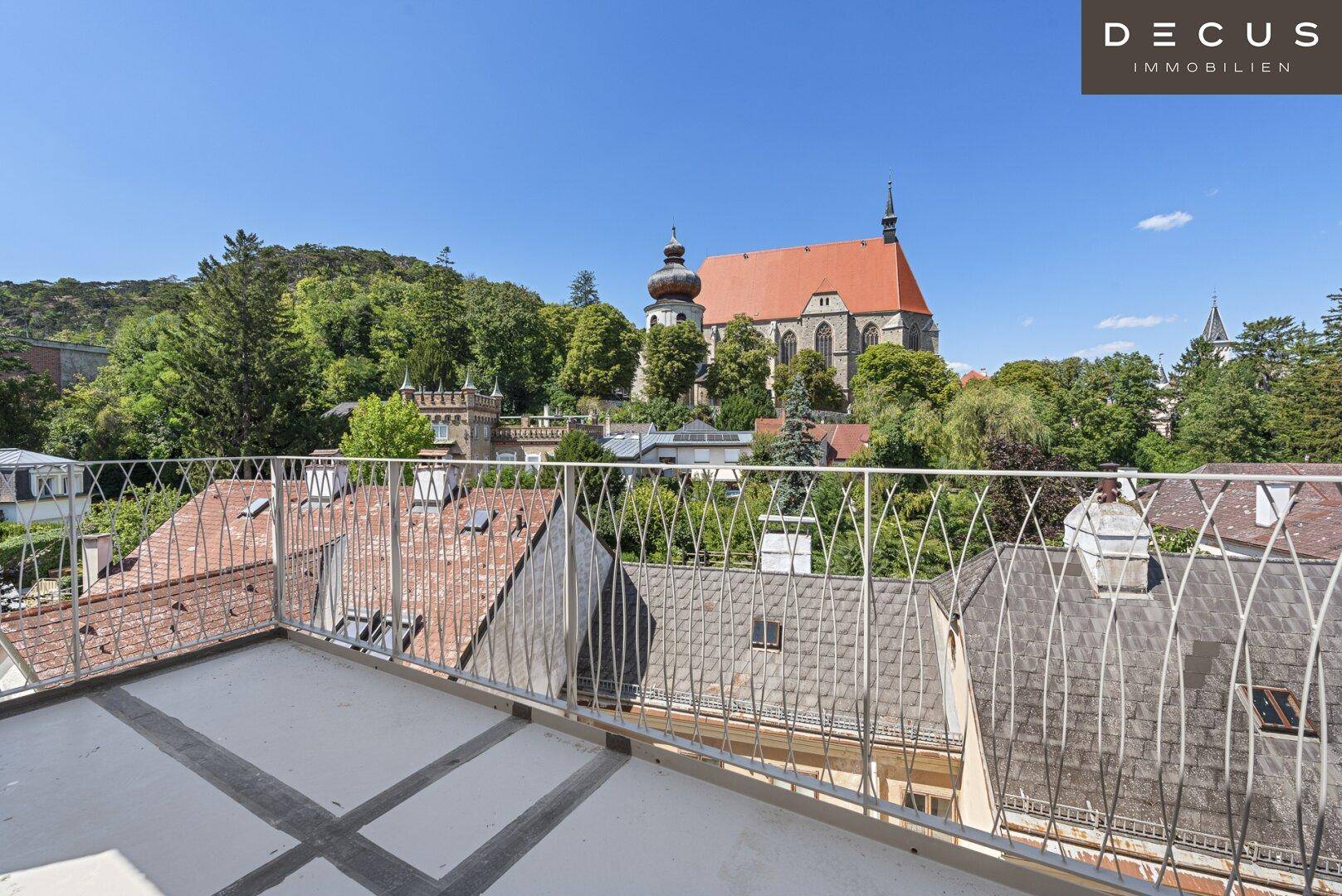 Weitläufige Dachterrasse mit Metallgeländer und Panoramablick über die Dächer der Stadt.