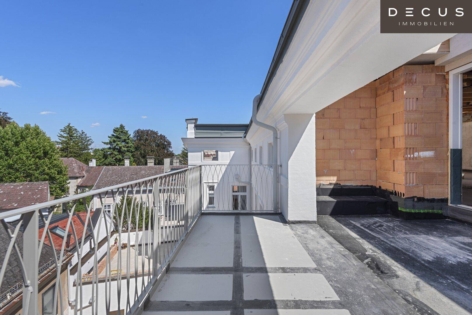 Langer Balkon mit Metallgeländer und Blick auf die umliegenden Gebäude.