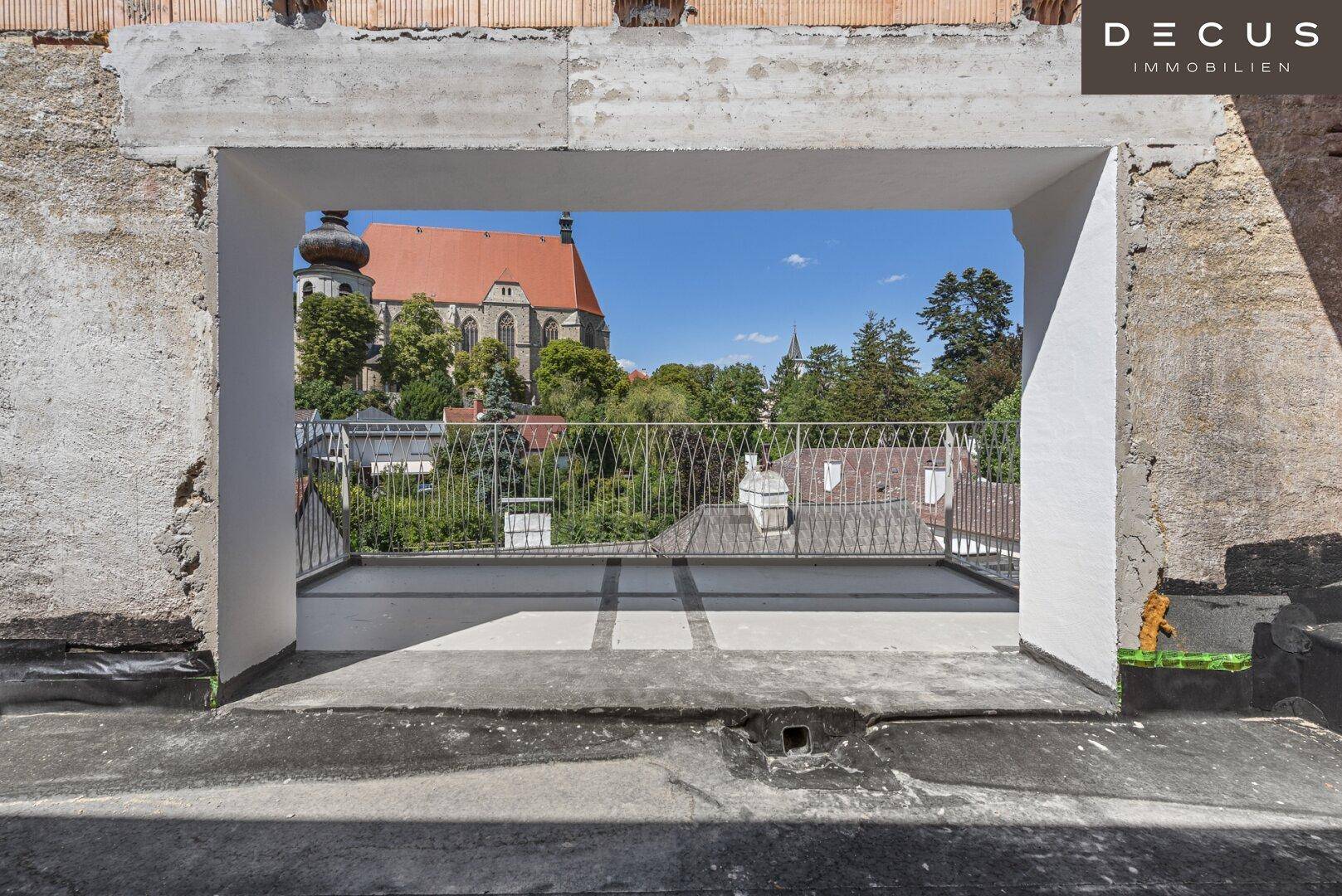 Dachterrasse im Rohbau mit weitem Blick auf die Stadt und historische Architektur.